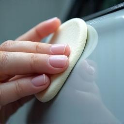 Close-up of a clay bar gliding over a car door panel.